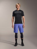 Alpinestars A-Aria Lite Short in Baja Blue, Men's MTB Shorts, worn with a black short-sleeve jersey and protective knee guards, featuring laser perforations for ventilation, mountain bike performance gear