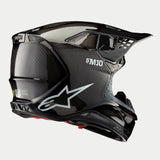 Alpinestars Supertech M10 Solid Helm, Motocross-Helm, glänzendes Carbon-Finish in Schwarz, mit weißem Astars-Logo und S-M10-Branding, aerodynamische Schale mit sichtbarem Carbonfaser-Gewebe und mehreren Belüftungsöffnungen