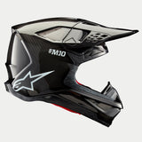 Alpinestars Supertech M10 Solid Helm, Motocross-Helm, Carbon Schwarz glänzend, Seitenprofilansicht mit glänzendem Carbonfaser-Gewebe, S-M10 Branding, weißes Alpinestars Stern-Logo, aerodynamisches Design mit Helmschild und Belüftungsöffnungen