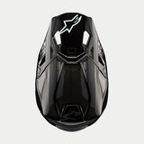 Alpinestars Supertech M10 Solid Helm, Motocross-Helm, Schwarz glänzendes Carbon, Ansicht von oben mit sichtbarem Carbonfaser-Gewebe, weißes Astars-Logo auf dem Visier, schlankes aerodynamisches Profil mit integrierten Belüftungsöffnungen