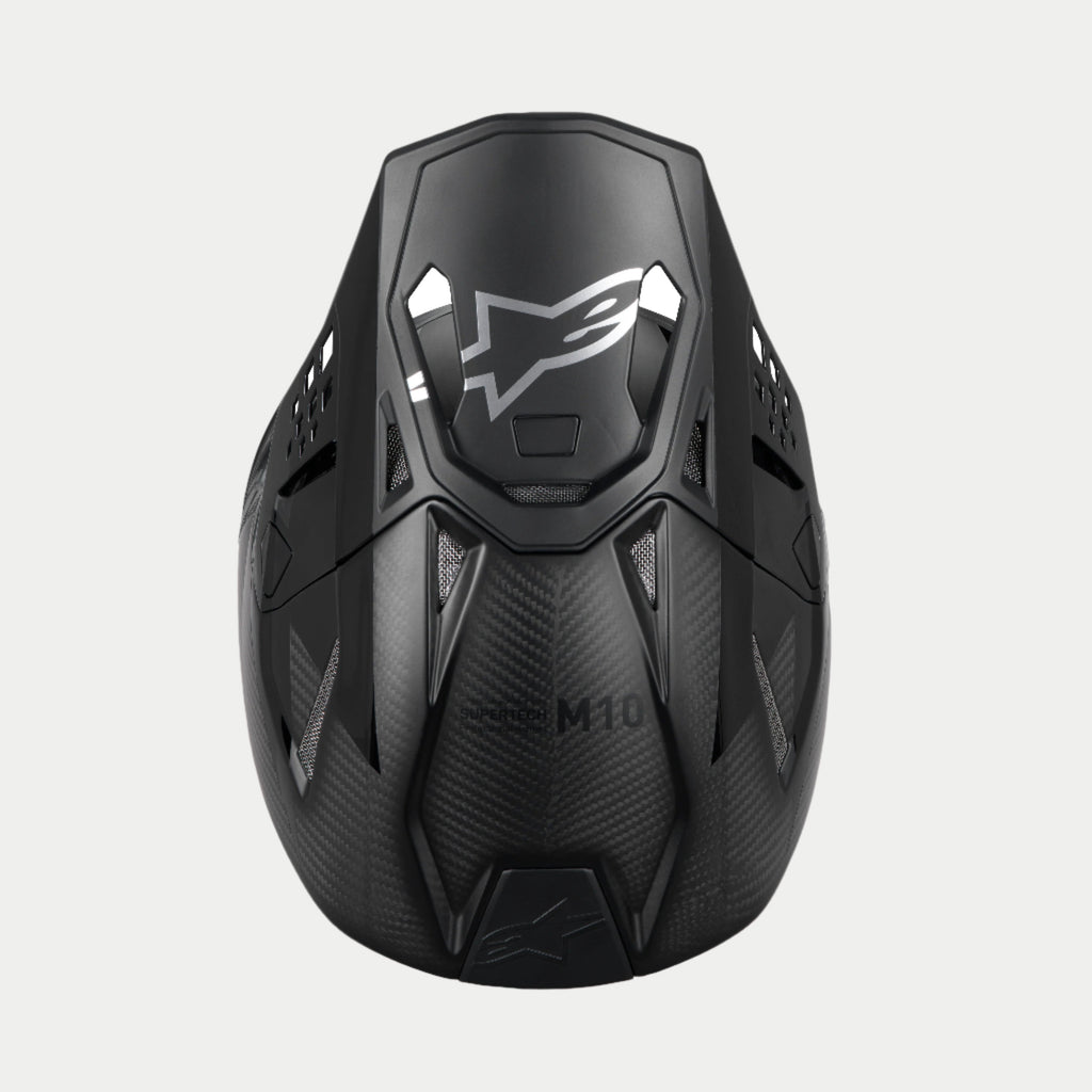 Alpinestars Supertech M10 Fame ECE 22.06 Helm, Motocross-Helm, Schwarz Carbon matt und glänzend, Draufsicht zur Hervorhebung des Carbonfaser-Gewebes, aerodynamisches Visier mit silbernem Alpinestars-Logo und mehreren Belüftungsöffnungen für den Offroad-Rennsport.