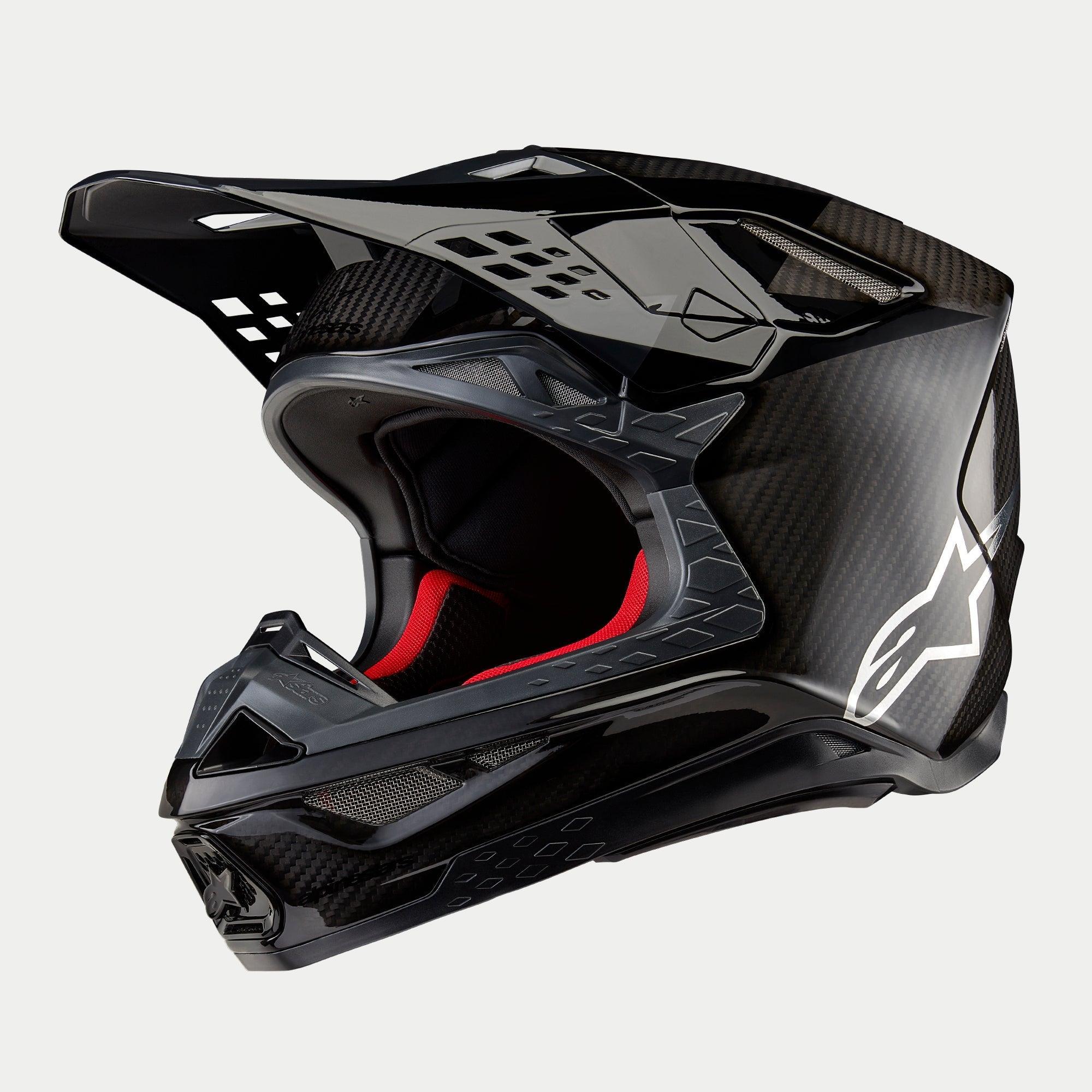 Alpinestars Supertech M10 Fame ECE 22.06 Helm, Motocross-Helm, Schwarz-Carbon in mattem und glänzendem Finish, mit sichtbarem Carbonfaser-Gewebe, weißem Astar-Logo an der Seite und roter Innenpolsterung, aerodynamisches Offroad-Design