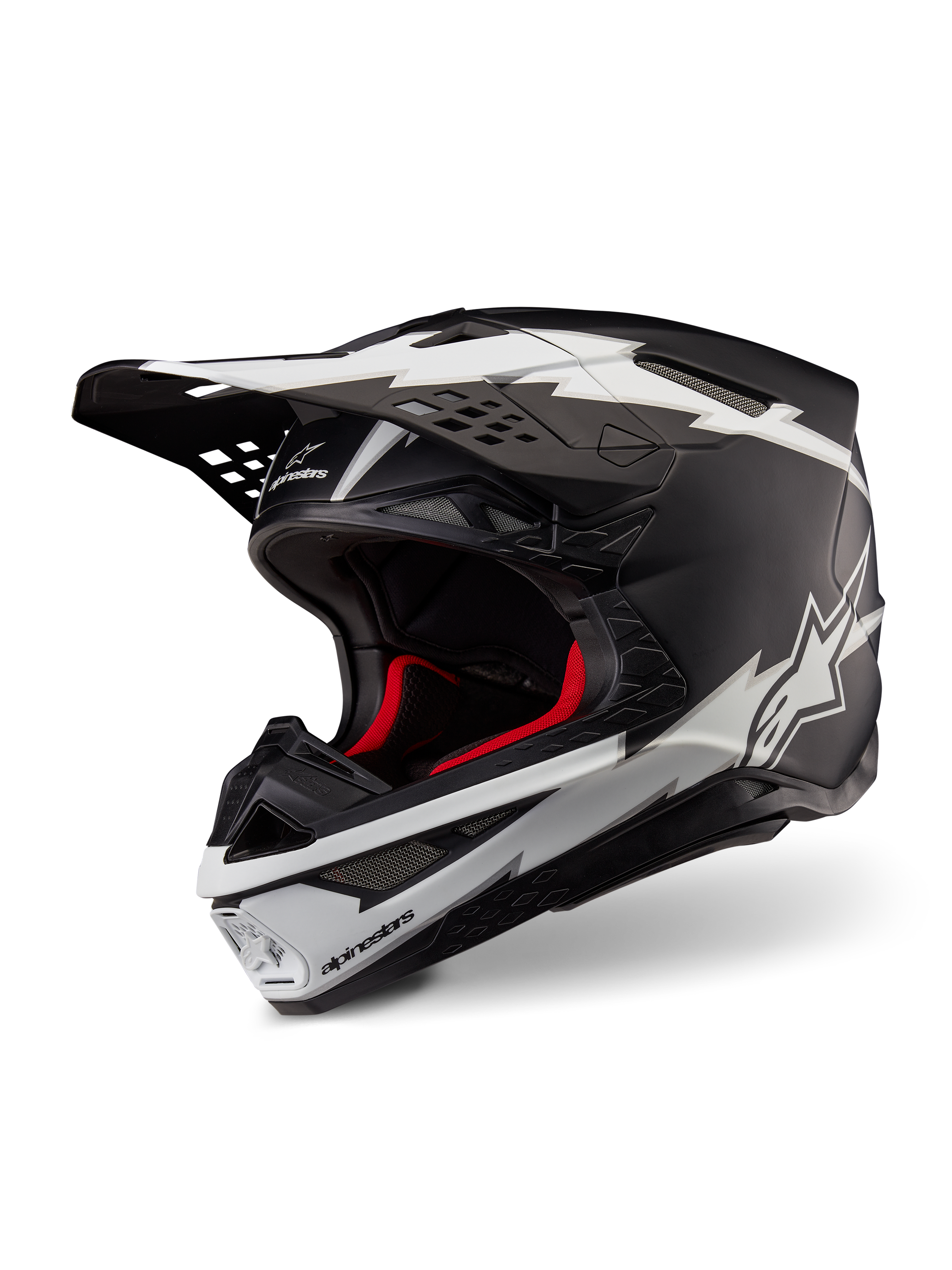 Alpinestars Supertech M10 Ampress Helm, Motocross-Helm, Schwarz und Weiß Matt, mit markanten weißen Blitz-Grafiken und Stern-Logos, rotem Innenfutter, Mehrkomponenten-Karbonschale mit aerodynamischem Profil