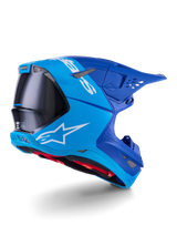 Alpinestars Supertech M10 Flood Helm, Motocross-Helm, Hellblau und Marineblau mit sichtbarer schwarzer Carbonfaser, Rückseiten-Profil mit Belüftungsöffnungen und weißem Logo, rotes Innenfutter, fortschrittliches aerodynamisches Design für Offroad-Performance