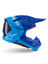 Alpinestars Supertech M10 Flood Helm, Motocross-Helm, Metallic-Blau und Mittelblau mit schwarzen Carbon-Akzenten, Seitenansicht, mit weißem Logo, aerodynamisches Design mit Belüftungsöffnungen, Details mit Carbonfaser-Textur, professioneller Schutz für den Offroad-Rennsport