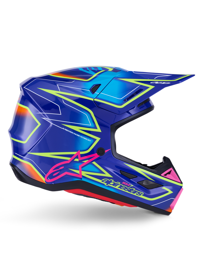 Alpinestars S-M7 Cast Helm, Motocross-Helm, Blau, Pink und Gelb Fluo glänzend, Seitenprofil mit markanten geometrischen Mustern, pinkfarbenem Alpinestars-Logo und belüfteter aerodynamischer Schale.