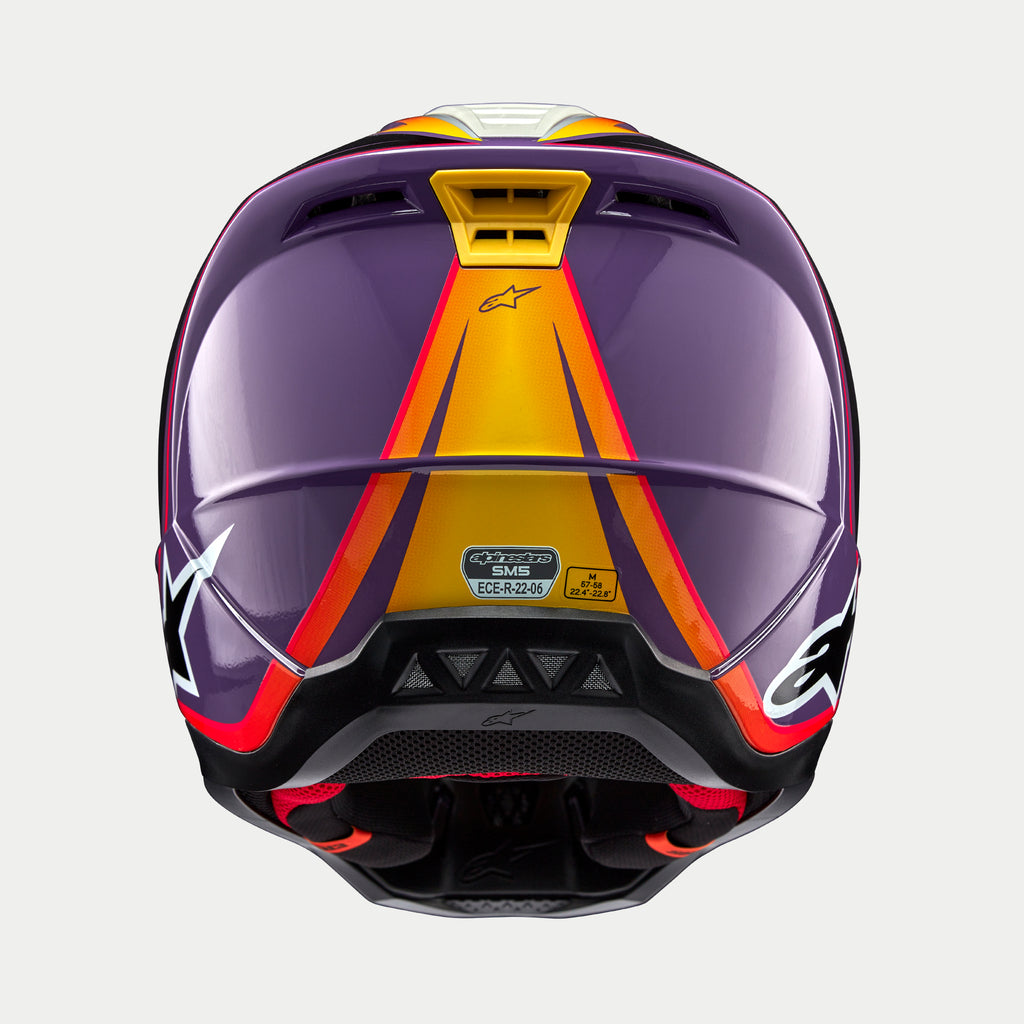 Alpinestars S-M5 Sail Helm ECE, Motocross-Helm, Lila Schwarz Silber Glänzend, Rückansicht mit orange-gelben Verlaufs-Grafiken auf violetter Schale, glänzendes Finish, weiße Stern-Logos an den Seiten, Belüftungsöffnungen und ECE-Zertifizierungsaufkleber.