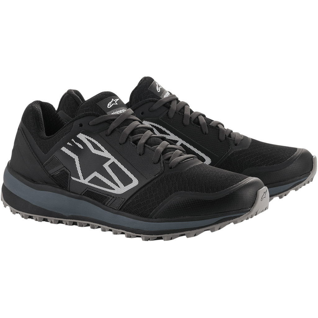 Alpinestars Meta Trail Schuhe, Performance-Laufschuhe, Schwarz und Dunkelgrau, großes weiß gestreiftes Astars-Logo an der Seite, Schnürdesign mit einer robusten grauen Sohle, entwickelt für ganztägigen Komfort im Paddock