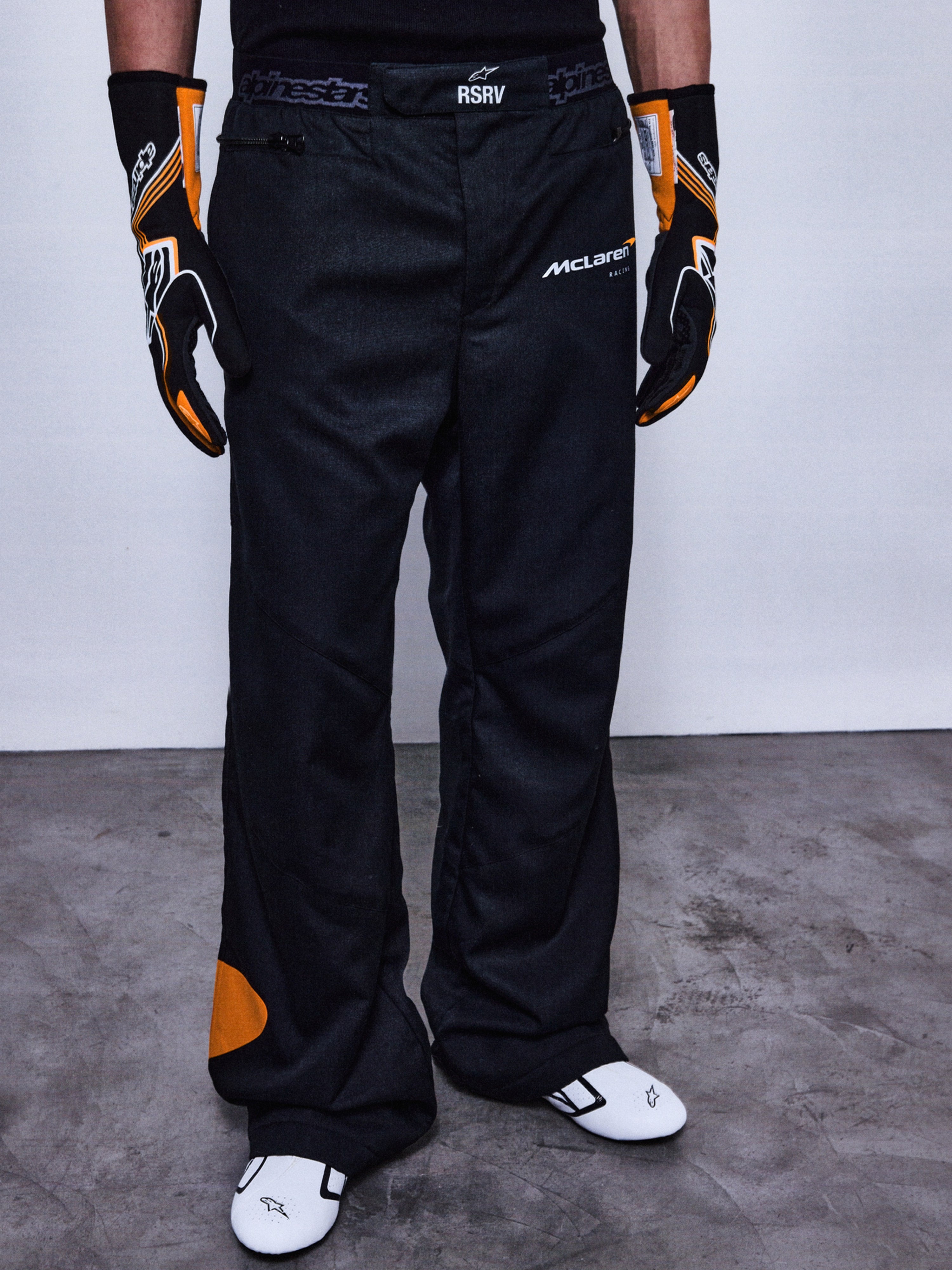 RSRV Arena Suit Pants, Schwarze Rennhose, McLaren und Alpinestars Logos, Orange Patches an der Seite, Orange Kniedetail, Motorsport-Performance-Hose