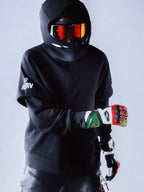RSRV Vault Hoodie, Premium Streetwear Kapuzenpullover, Schwarz, Unisex, Motorsport-inspiriertes Design mit reflektierendem Logo, Person mit Helm und Handschuhen, urbaner Lifestyle-Look