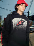 Alpinestars Obsessed Hoodie, schwarzer Fleece-Kapuzenpullover, weiße MX-Farbverlaufsgrafik auf der Brust mit rotem Stern-Logo, rote Wortmarken-Logos auf den Ärmeln, lässige, vom Motorsport inspirierte Streetwear in einer städtischen Umgebung