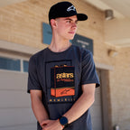 Alpinestars Galun CSF Tee, Short Sleeve T-Shirt, Charcoal, front vintage gas can graphic with 'astars' branding and 'MCMLXIII' Roman numerals, worn by a man with a black logo cap, casual motorsport lifestyle