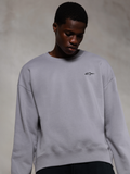 Alpinestars Essentials Ageless Crew, hochwertiges Rundhals-Sweatshirt in Silber, mit einem kleinen schwarzen Alpinestars-Logo auf der Brust, von einem Model getragen, lässige Lifestyle-Streetwear mit weicher Fleece-Textur.