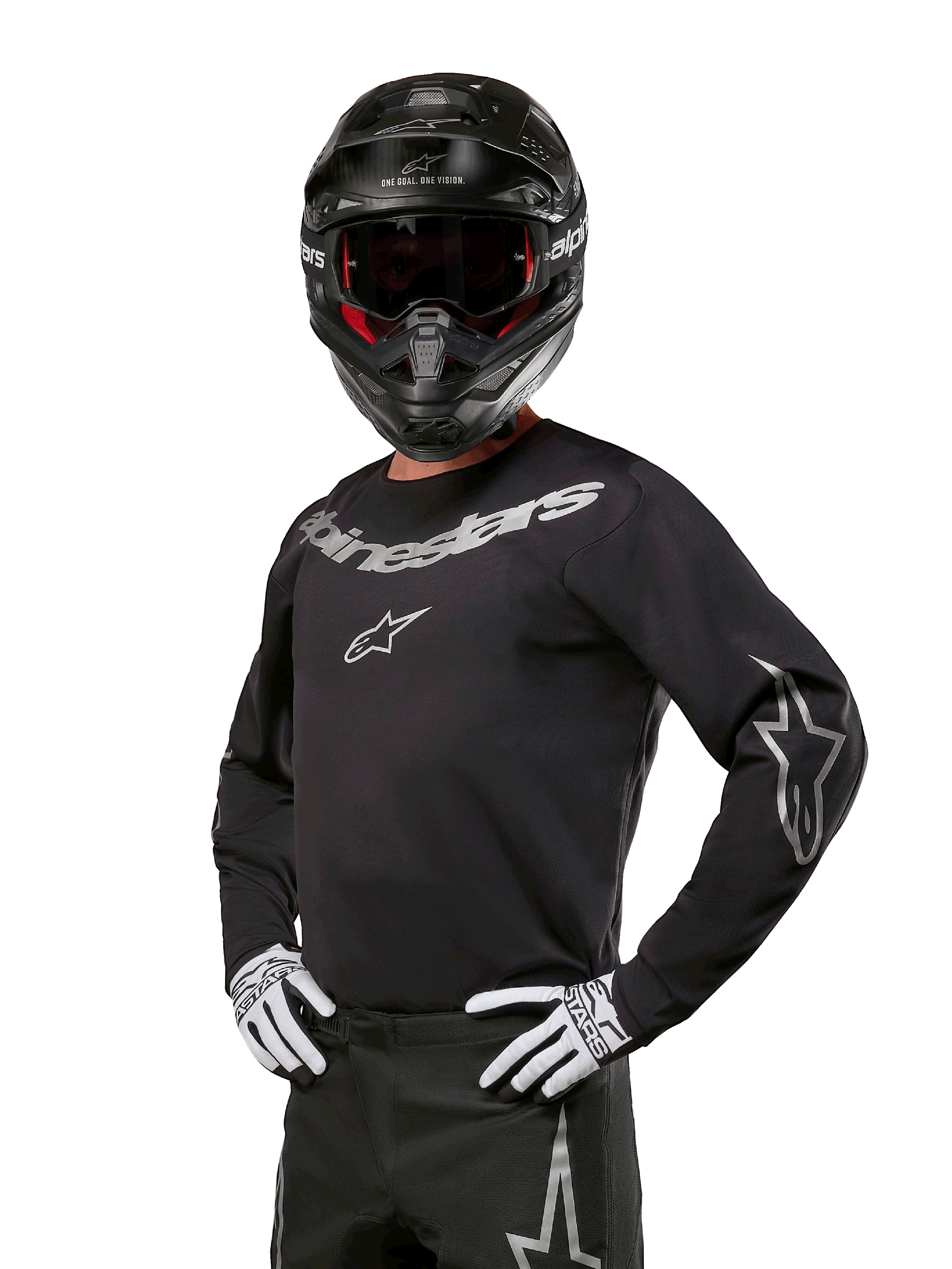 Alpinestars 2024 Fluid Graphite Jersey, Motocross-Trikot in Schwarz und Silber, langärmelige Performance-Passform, getragen mit schwarzem Helm und weißen Handschuhen, silbernes Alpinestars-Branding, Offroad-Rennausrüstung
