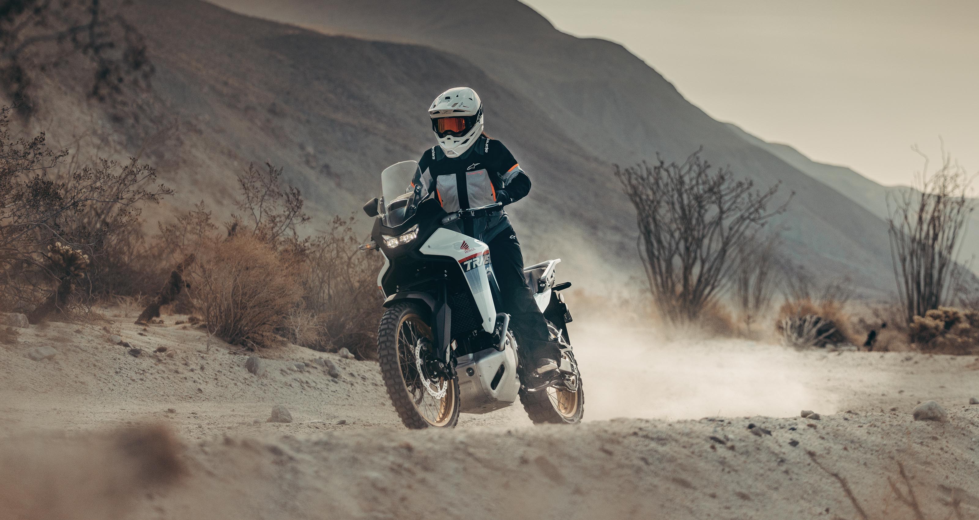 Alpinestars Stella Andes V4 Drystar® Jacket and Pants, Women's Gray and Black Waterproof Adventure Gear on a desert trail.