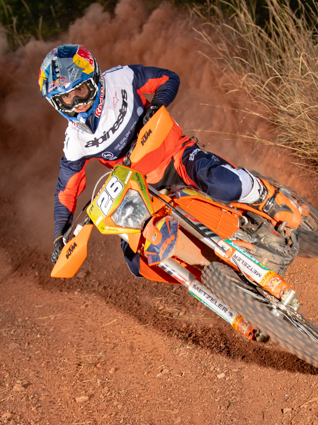 Enduro-Fahrer in Aktion auf einem orangefarbenen Dirtbike, trägt das Alpinestars Pro-Dura Jersey in Navy, Hot Orange und Weiß, mit einem leichten und atmungsaktiven Design sowie markantem Branding für Offroad-Performance.