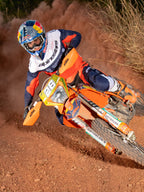 Enduro-Fahrer in Aktion auf einem orangefarbenen Dirtbike, trägt das Alpinestars Pro-Dura Jersey in Navy, Hot Orange und Weiß, mit einem leichten und atmungsaktiven Design sowie markantem Branding für Offroad-Performance.