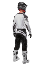 Alpinestars 2024 Racer Hana Hose, Motocross-Hose, Schwarz und Weiß mit markantem Logo-Schriftzug am Gesäß, Rückansicht der kompletten MX-Ausrüstung inklusive weißem Trikot und Stiefeln