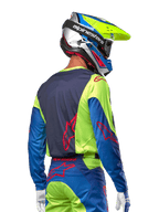Motocross rider wearing the Alpinestars 2024 Racer Hoen Jersey in Yellow Fluo and Blue Night Navy, featuring a red star logo on the back, matching motocross pants, and a coordinated racing helmet, back view showcasing the ergonomic design for off-road performance.