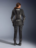 Alpinestars Stella GP-R7 2-Teiler Lederkombi, Damen-Motorradanzug, Schwarz mit weißen Akzenten, Rückansicht mit aerodynamischem GP-R7 Höcker und Tech-Air Ready-Branding, weiße Alpinestars-Logos an den Ärmeln, Akkordeon-Stretcheinsätze, getragen mit schwarzen Rennstiefeln