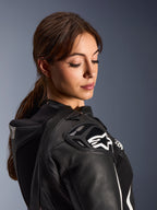 Frau im Alpinestars Stella GP-R7 2-Teiler-Lederanzug, Nahaufnahme der schwarzen Lederschulter mit DFS RR Panzerung und weißem Stern-Logo, mit integriertem Aero-Höcker und perforierten Details.