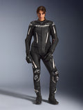 Frau im Alpinestars Stella GP-R7 2-Teiler Lederanzug in Schwarz mit weißen Akzenten, mit perforierten Lederpaneelen und weißem Branding auf Brust und Knien, kombiniert mit passenden schwarzen Rennhandschuhen und Stiefeln, professionelle Motorrad-Rennausrüstung