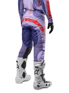 Alpinestars 2024 Techstar Ocuri Hose, Motocross-Hose, Lila und Hot Orange, Rückansicht mit markantem Alpinestars-Schriftzug auf dem Gesäß, weiße Stiefel, schwarze Handschuhe, professionelle Offroad-Ausrüstung