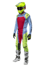 Motocross-Fahrer in Alpinestars 2024 Techstar Ocuri Hose in Hellblau, Fluo-Gelb und Beerenrot, koordinierte Rennausrüstung mit passendem Jersey, neongelbem Helm und weißen Stiefeln, Vorderansicht eines Offroad-Wettbewerbsoutfits.