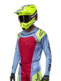 2024 Techstar Ocuri Jersey, Motocross-Rennsport-Trikot, Hellblau mit roten und neongelben Akzenten, getragen mit passendem neongelbem Helm und schwarzer Brille, mit schwarzen Alpinestars-Logos auf Brust und Schultern, sportliches, rennsportinspiriertes Design für Offroad-Performance