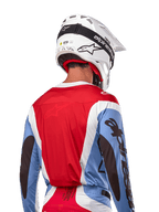 Alpinestars 2024 Techstar Ocuri Trikot, Motocross-Trikot, Hellblau, Marsrot und Weiß, Rückansicht eines Fahrers mit passendem weißem Helm und schwarzer Schutzbrille, markantes schwarzes Branding an den Ärmeln und ergonomische Race-Passform für Offroad-Performance