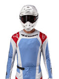 Alpinestars 2024 Techstar Ocuri Trikot, Motocross-Renntrikot, Hellblau, Mars-Rot und Weiß, Vorderansicht mit lasergeschnittener Belüftung und athletischer Passform, getragen mit weißem Helm und Brille für einen professionellen Offroad-Rennlook