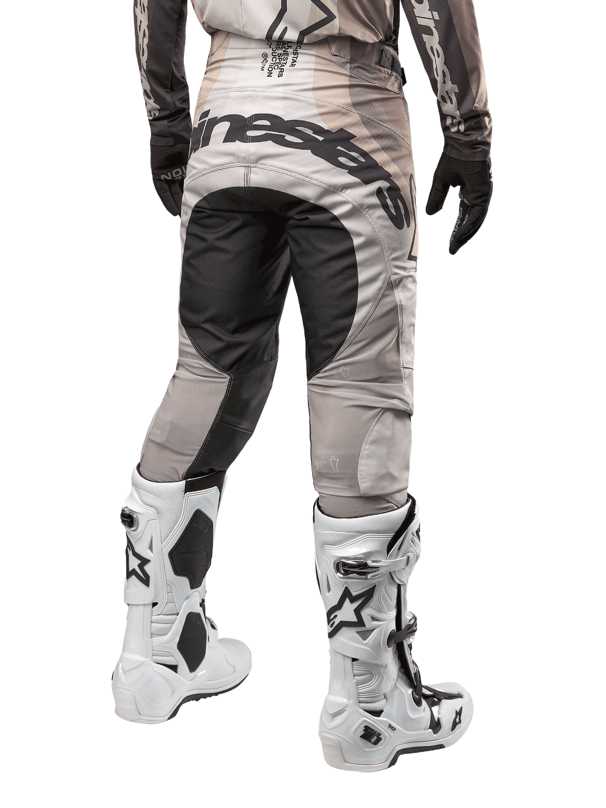 Alpinestars 2024 Techstar Pneuma Hose, Motocross-Hose, Dark Sand und Iron Dust Gray, Rückansicht von der Taille abwärts, auffälliges schwarzes Alpinestars-Branding am Gesäß, kombiniert mit weiß-schwarzen Motocross-Stiefeln und schwarzen Handschuhen, strapazierfähiges Race-Fit-Design für den Offroad-Wettbewerb