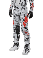 Alpinestars 2024 Techstar Rantera Hose, Motocross-Hose, Haze Gray Camo mit schwarzem und rotem abstraktem Muster, getragen mit passendem Jersey, schwarzen Handschuhen und weißen Motocross-Stiefeln, konzipiert für Hochleistungs-Offroad-Rennsport