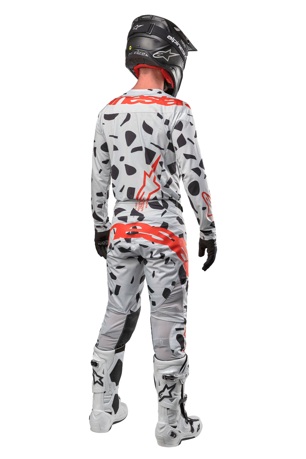 Motocross-Fahrer von hinten in Alpinestars 2024 Techstar Rantera Hose, Haze Gray Camo mit schwarzen Flecken und roten Logos, passendes Trikot, schwarzer Helm und weiße Stiefel, komplettes Offroad-Rennoutfit