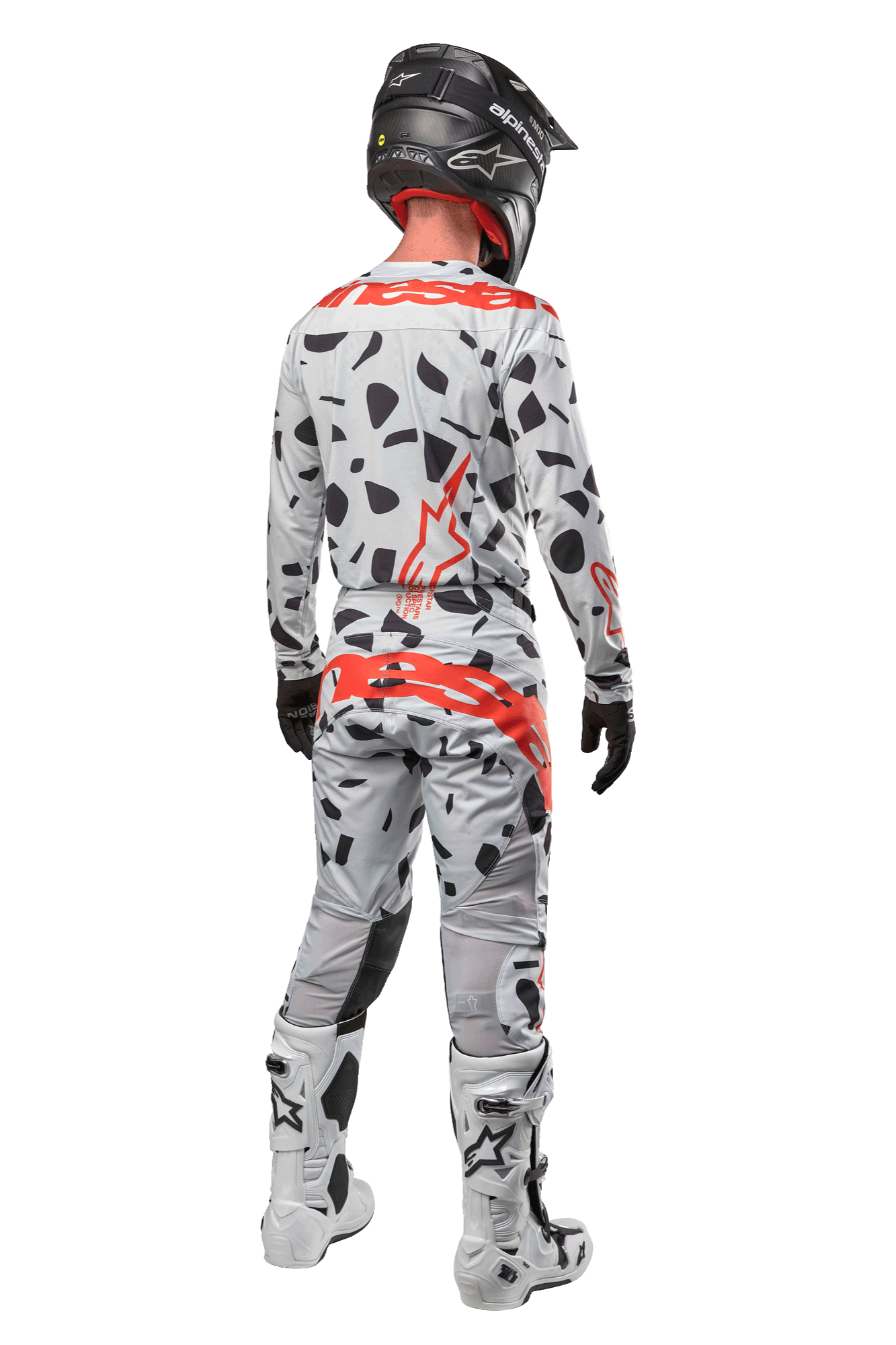 Motocross-Fahrer von hinten in Alpinestars 2024 Techstar Rantera Hose, Haze Gray Camo mit schwarzen Flecken und roten Logos, passendes Trikot, schwarzer Helm und weiße Stiefel, komplettes Offroad-Rennoutfit