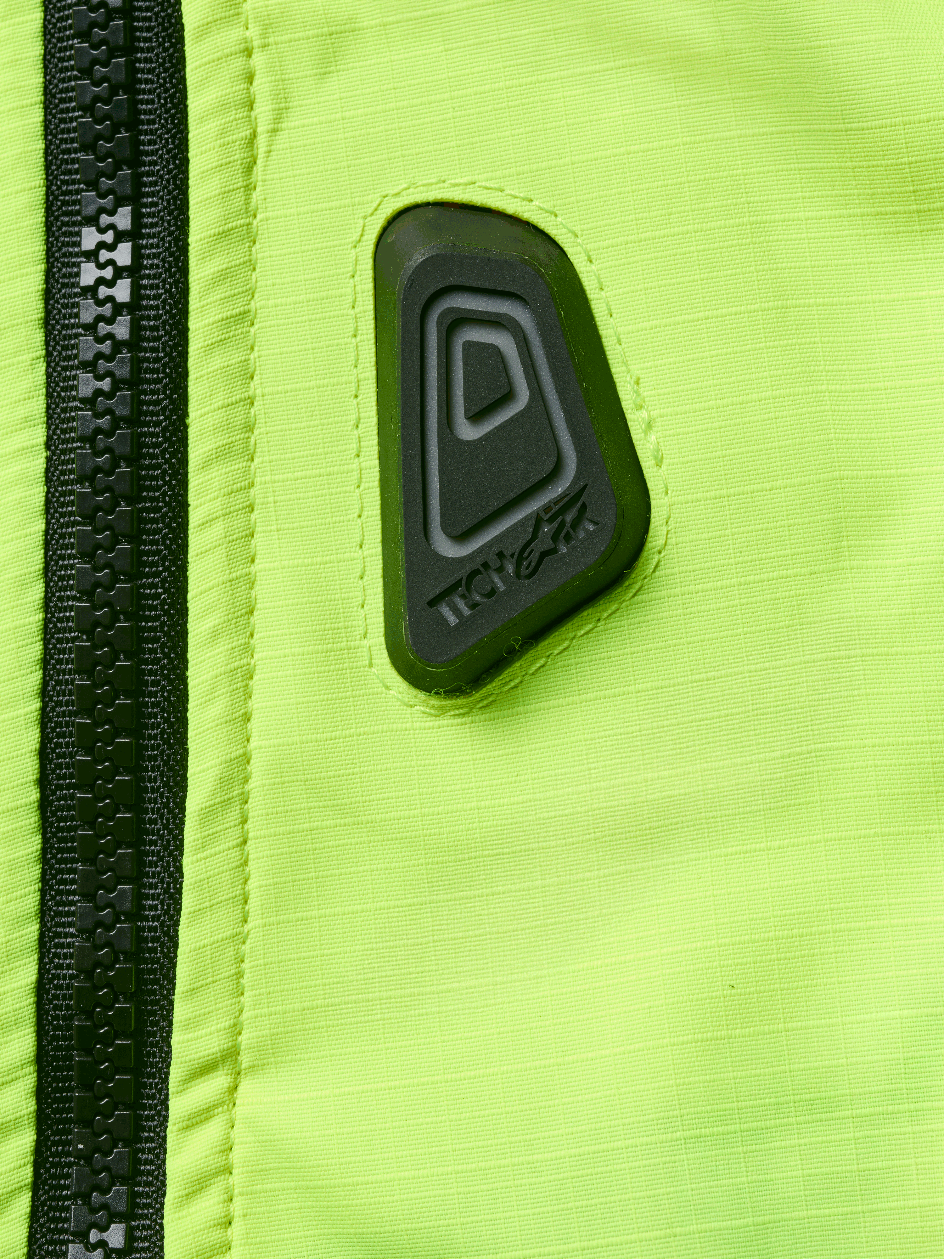 Alpinestars Tech-Air® 3 V2 System, Motorcycle Airbag Vest, Close-up of Yellow Fluo water-resistant fabric with black zipper, featuring a black rubberized Tech-Air logo patch, high-visibility safety gear