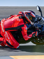 Alpinestars GP Plus V4 Sprint Lederkombi, Tech-Air® Ready, Fluo-Rot und Weiß, Motorradfahrer in Schräglage auf Rennstrecke.