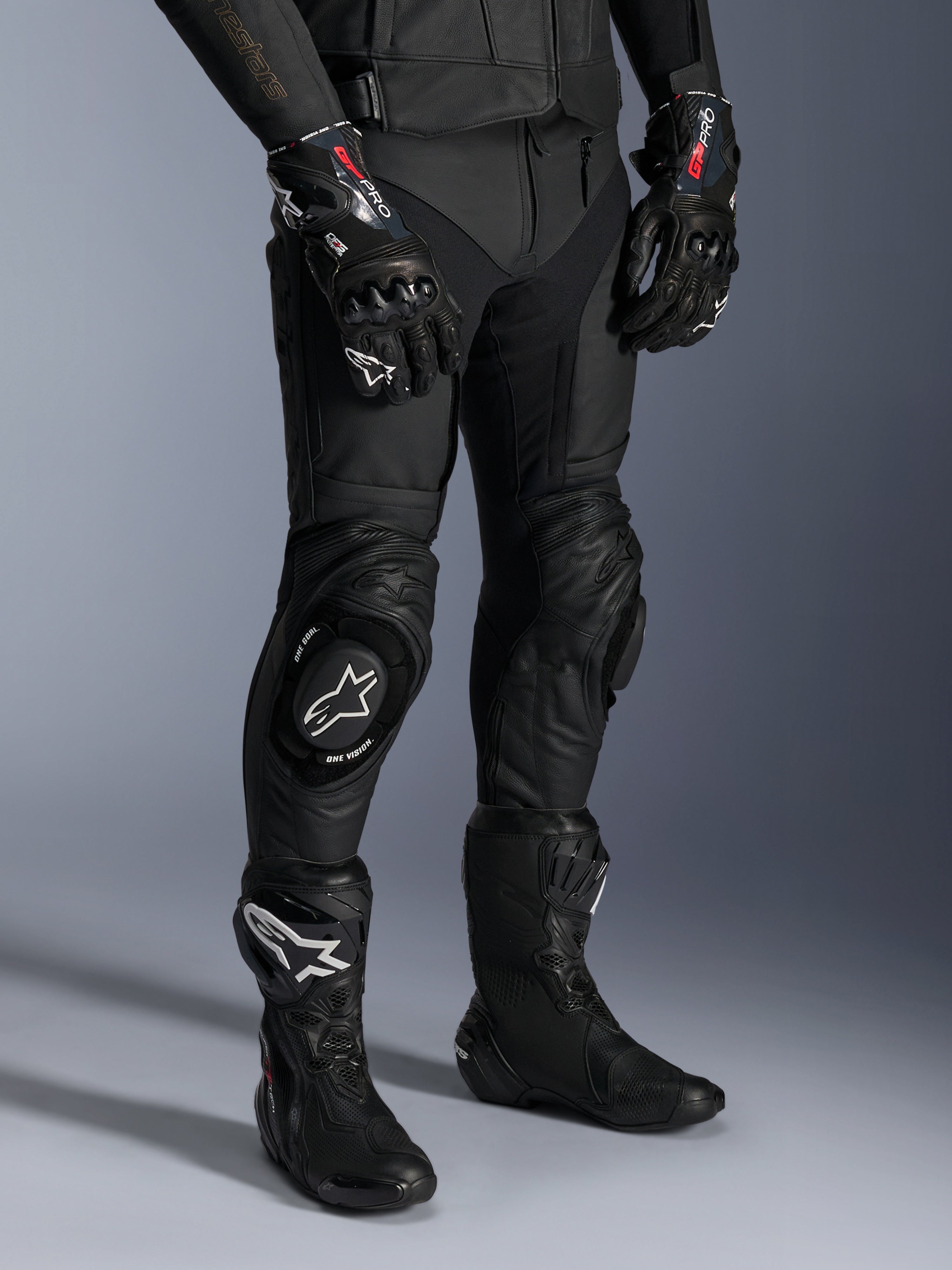 Missile V3 Leather Pants, Black Motorcycle Racing Pants, worn with matching GP Pro gloves and technical racing boots, premium leather construction with white logo knee sliders, professional racing aesthetic for track and road use