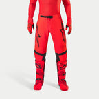 Alpinestars Supertech Ember LE Hose, Motocross-Hose, Red Fluo und Hellrot mit schwarzen Akzenten, mit markanten schwarzen Stern-Logos auf den Oberschenkeln, schwarzer Taillenschnalle und Kniepaneelen, getragen mit passenden roten Stiefeln und Handschuhen für ein koordiniertes Renn-Outfit.