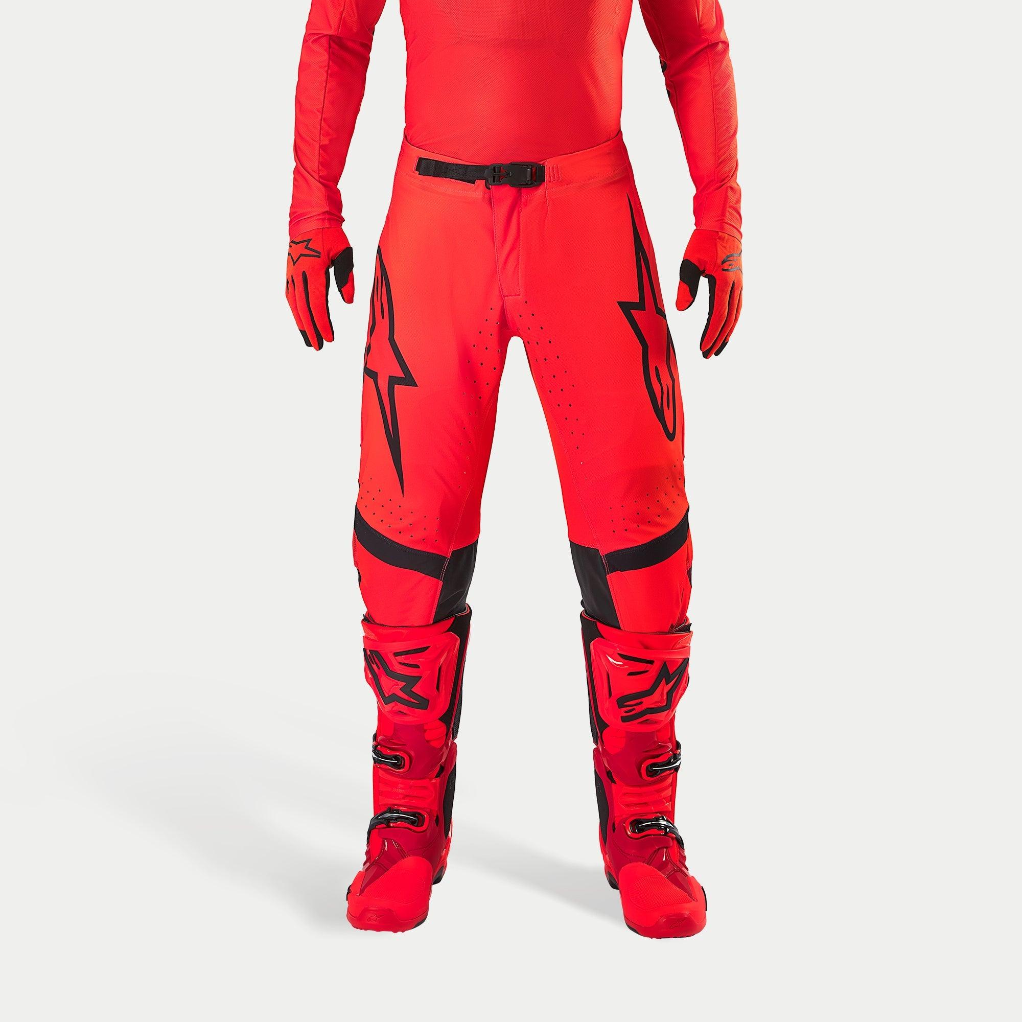 Alpinestars Supertech Ember LE Hose, Motocross-Hose, Red Fluo und Hellrot mit schwarzen Akzenten, mit markanten schwarzen Stern-Logos auf den Oberschenkeln, schwarzer Taillenschnalle und Kniepaneelen, getragen mit passenden roten Stiefeln und Handschuhen für ein koordiniertes Renn-Outfit.
