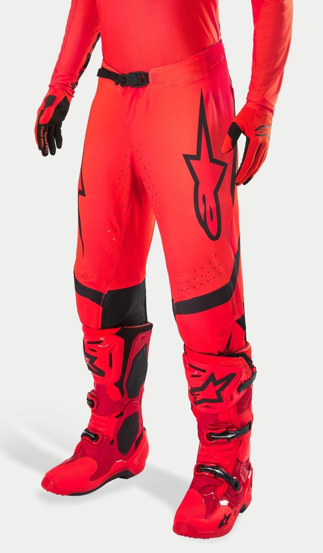 Alpinestars Supertech Ember LE Motocross Pants, Red Fluo and Bright Red with Black accents, worn with matching red racing boots and gloves, featuring a prominent black star logo on the leg, secure waist buckle, and perforated zones for ventilation.